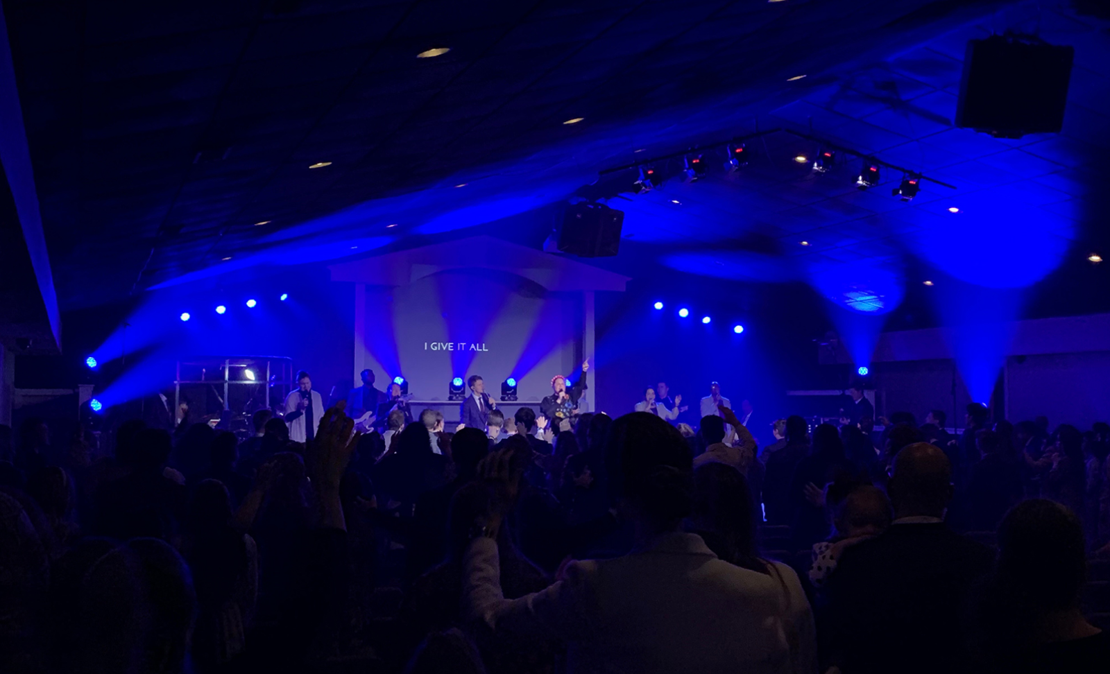 Crowded church interior with blue stage lights.