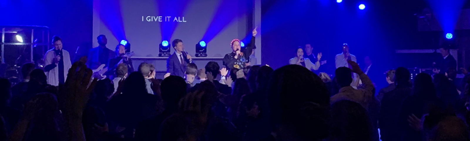People gathering around stage with blue stage lights