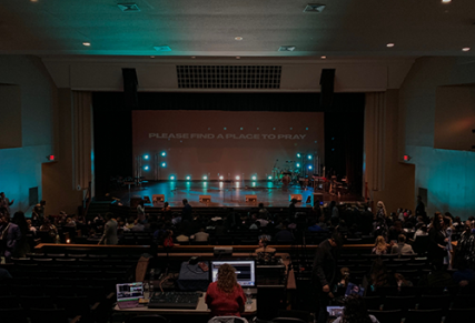 Church stage with back lighting, featuring a stage worker managing the lights on computer
