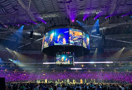Big scoreboard screen in center of arena with beam lighting around it