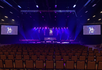 Dark arena with purple lit stage with screens on either side.
