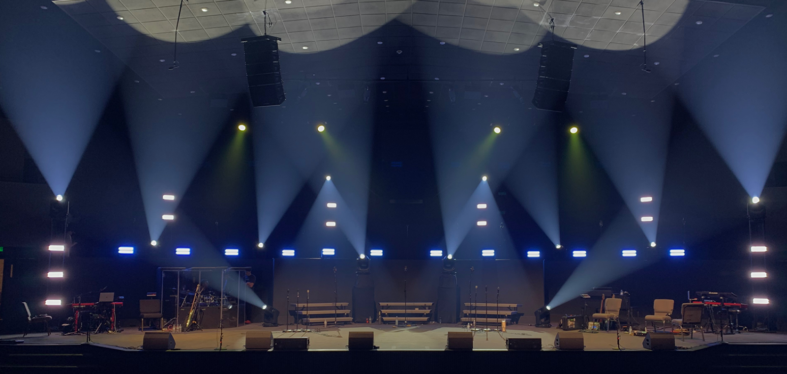 Stage with instruments, and musical equipment being lit with light beams