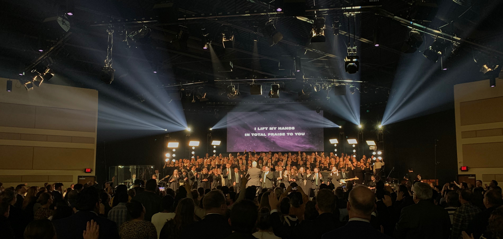 Stage with choir and musicians performing with white light beams
